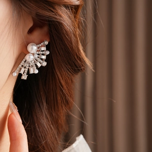 Detailed view of silver fan-shaped earrings with pearls and rhinestones on ear