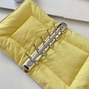 Detail of yellow quilted binder cover with silver 6-ring metal mechanism inside
