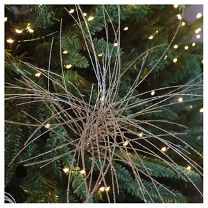 Close-up of golden glitter starburst branch decoration on a festive Christmas tree