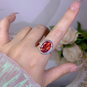 Close-up of luxury halo ring with oval red gemstone and white zircon setting