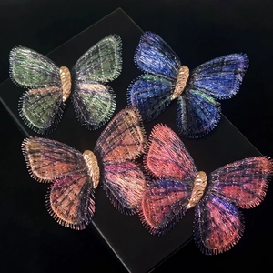 Macro view of four luxury fabric butterfly brooches with intricate woven texture and gold metal