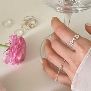 Detail showing sterling silver chain link and olive bead rings in an elegant lifestyle setting