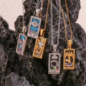 Macro detail of 18K gold and silver Tarot card necklaces on dark volcanic rock