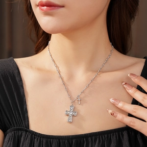 Detail of silver double cross necklace with zircon inlay worn by a model on a black top