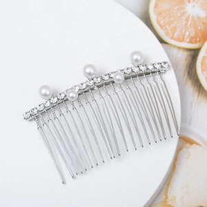 Elegant silver hair comb with sparkling rhinestones and white pearls on white stand