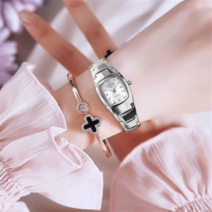 Macro shot of a tonneau-shaped silver quartz watch paired with a clover bangle