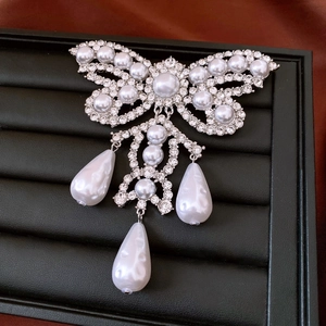 Detailed macro view of butterfly pearl brooch with rhinestones and teardrop pendants