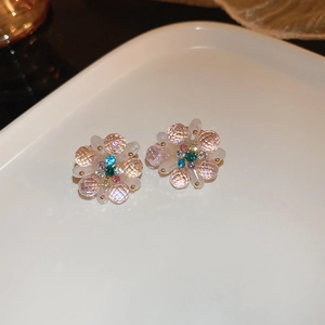 Gros plan de boucles d'oreilles fleur colorées avec cristaux sur un plateau blanc