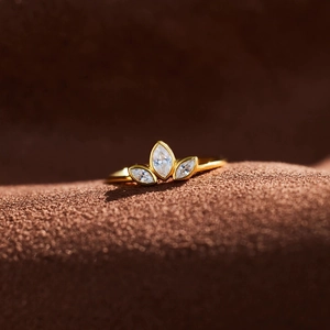 Macro side view of golden clover leaf ring with marquise cut gemstones on brown suede