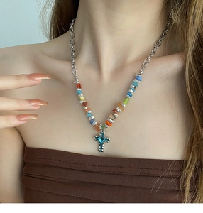Detailed close-up of a blue heart cross pendant on a silver chain with colorful stones