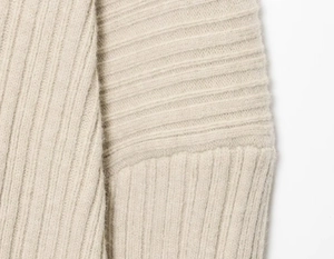 Close-up of beige ribbed knit sweater showing detailed texture and stitching quality