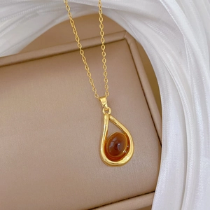Macro detail of amber pendant necklace on silk with gold teardrop crystal design