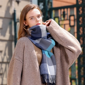 Colorful checkered knit scarf with tassels paired with a brown coat in an outdoor setting