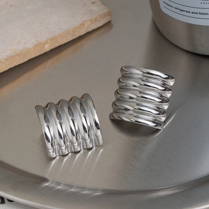 Macro shot of silver wide-band rings with textured wave pattern on metallic tray