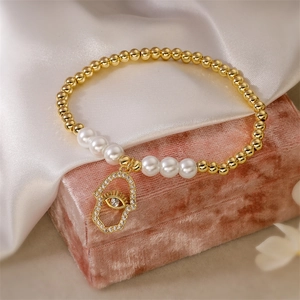 Détail d'un bracelet de perles dorées avec pendentif Hamsa sur boîte en velours