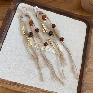 Bohemian tassel earrings with zircon studs and earthy beads in a rustic linen tray
