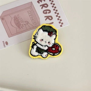 Detail showing hand embroidered white cat patch with a red donut and yellow border
