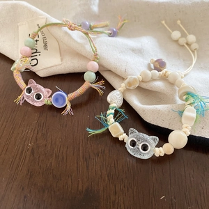 Detail of handmade woven bracelets with ceramic cat charms and adjustable tassel closure