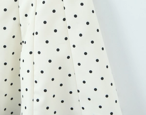 Detailed macro view of white dress fabric with black polka dots and delicate pleats