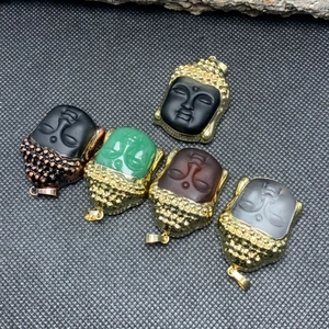 Detailed macro view of assorted crystal Buddha head pendants with gold metal trim