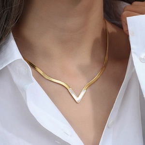 Macro detail of V-shaped gold necklace featuring white mother-of-pearl inlay