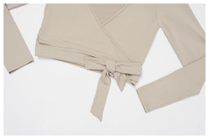 Detail of light beige wrap yoga top featuring a V-neck and stylish waist tie design
