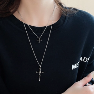 Detail of a silver double-layered cross necklace with a liquid texture cross pendant