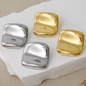 Detailed view of minimalist gold and silver square stud earrings on a stone base