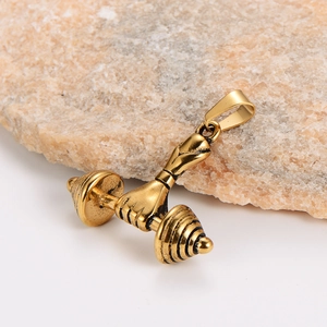 Golden hand holding dumbbell pendant on stone background, sporty stainless steel jewelry