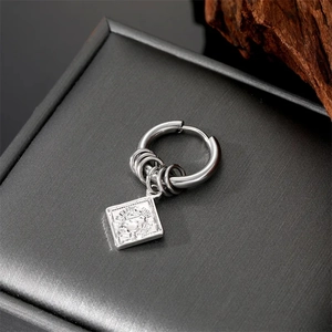 Macro detail of stainless steel hoop earring with Elizabeth II coin relief charm