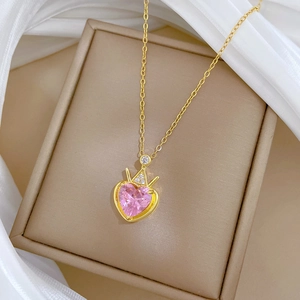 Elegant gold titanium necklace with pink heart gem and crown pendant on silk background