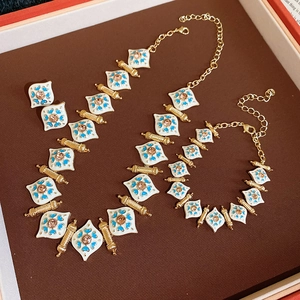 Detail view of vintage jewelry set with white enamel, blue patterns and amber stones