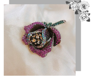 Detailed view of alloy rose brooch with purple rhinestones on cream silk fabric