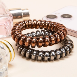 Metallic spiral hair ties in bronze and silver colors on a stylish minimalist background