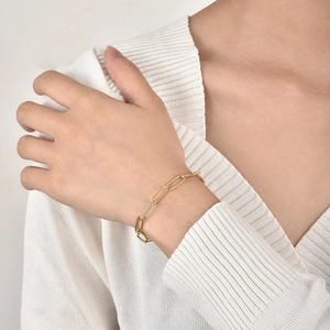 Goldenes Büroklammer-Kettenarmband mit Kristallen, am Handgelenk eines Models
