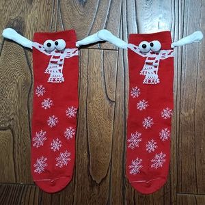 Detail of red knitted Christmas socks with snowflake patterns and 3D cartoon hand elements