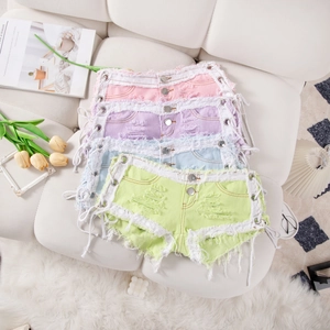 Detalle de pantalones cortos vaqueros rotos multicolores con cordones laterales y flecos