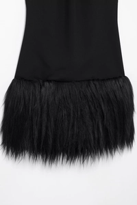 Detail eines schwarzen Cocktailkleids mit elegantem Kunstpelzbesatz am Saum der kurzen Robe