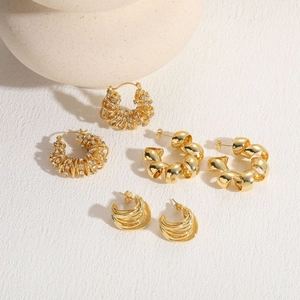 Detail view of 14K gold plated C-shaped twist earrings with zircon accents on stone base