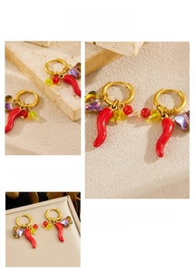 Detail of gold hoop earrings with red chili and purple butterfly charms on stone base