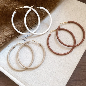 Three pairs of large hoop earrings with leather wrap detail in neutral autumn tones