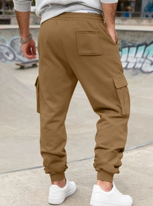 Back view of men's cargo sweatpants with flap pockets in a concrete skate park