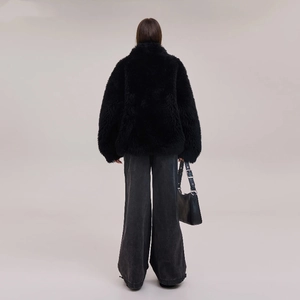 Rear view of black oversized faux fur coat and grey wide-leg jeans in minimalist style