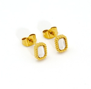 Détail de boucles d'oreilles dorées avec zircon et gravure S.Steel au verso