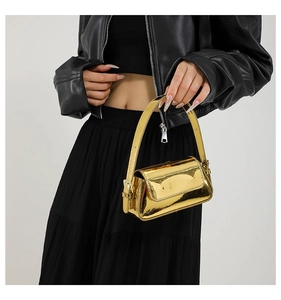 Detail of the golden mirror finish handbag with metallic luster on model's shoulder