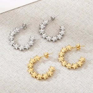 Minimalist star-shaped C-hoop earrings in gold and silver finish on textured fabric