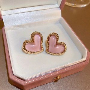 Detailed view of pink heart earrings with textured gold edges inside a gift box