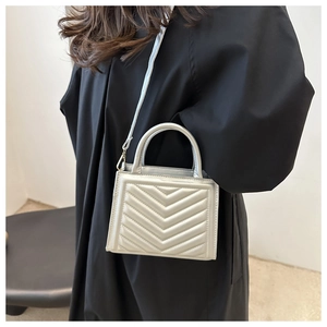 Silver chevron quilted handbag with metallic finish and top handle detail shown by model