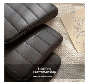 Detail of black quilted laptop sleeve showing refined stitching and anti-shock fabric texture