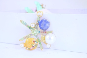 Detail shot of starfish and shell pendant with colorful enamel and faux pearls